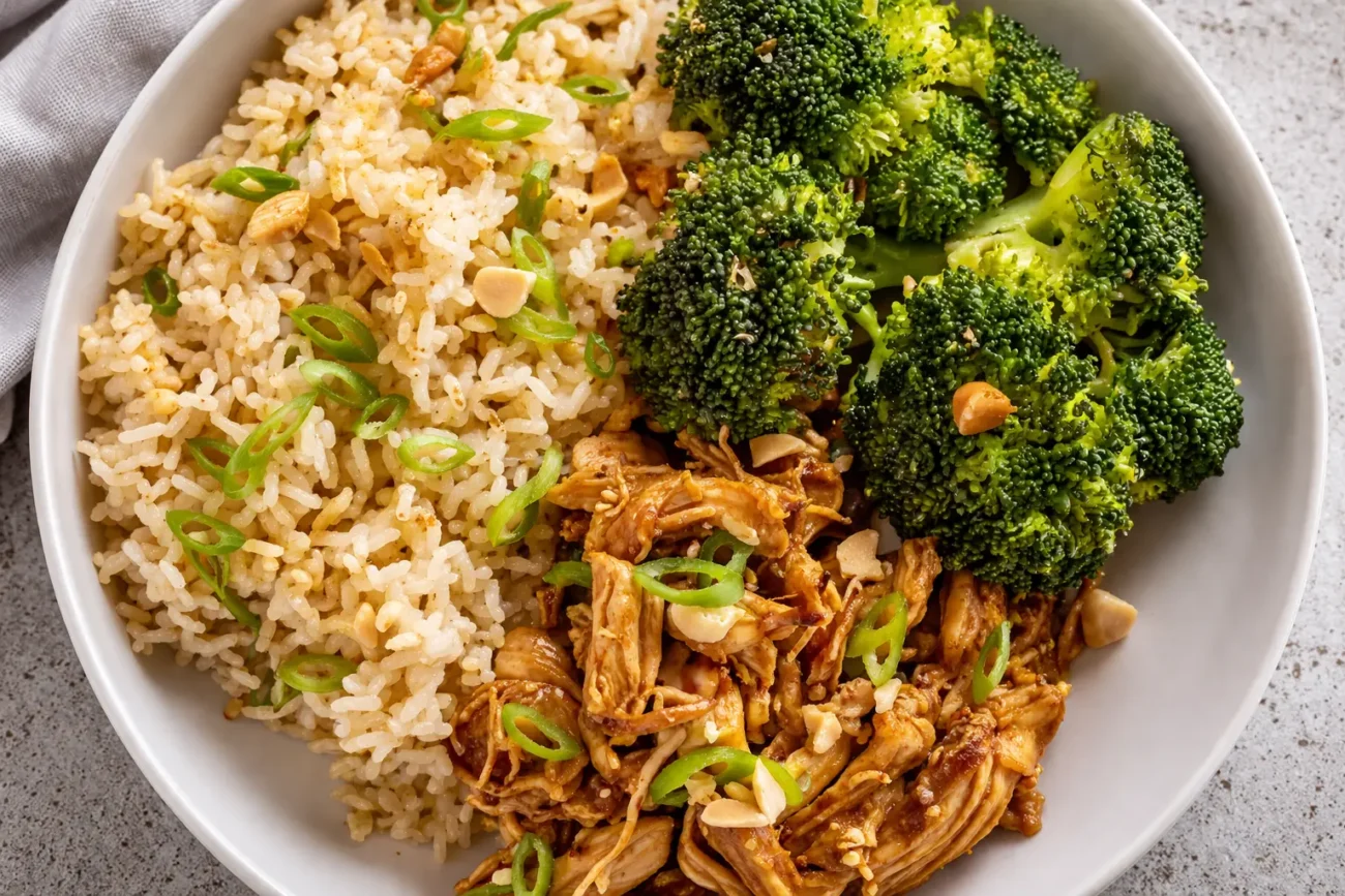 healthy chicken rice bowl with shredded chicken, broccoli and seasoned rice topped with green onions close-up